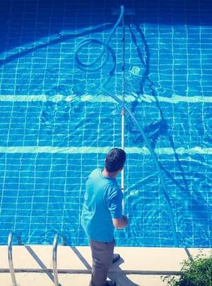 Technician skimming a swimming pool