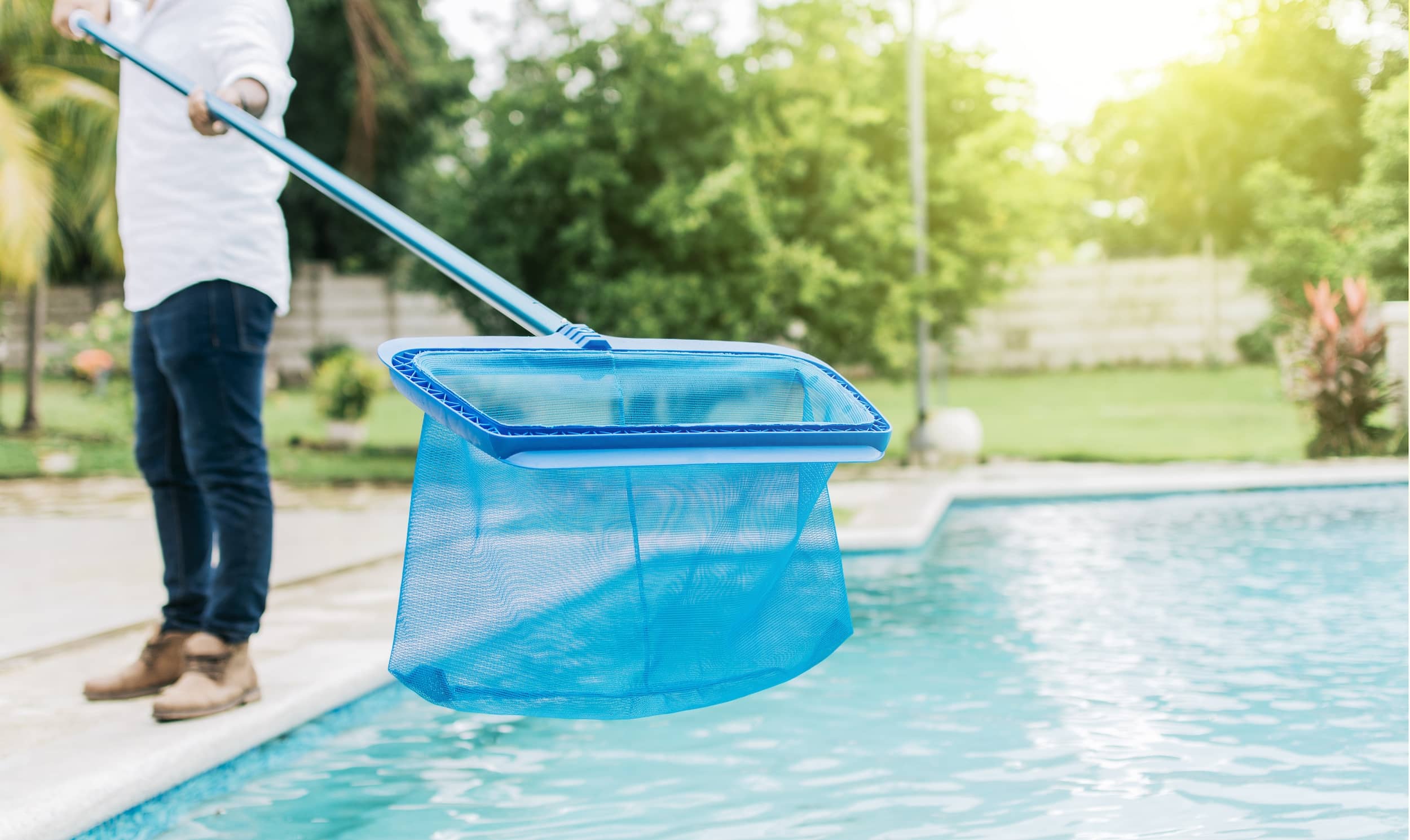 Pool maintenance technician cleaning a pool with a net