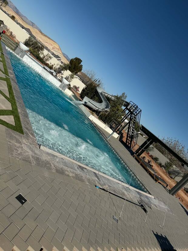 Luxury backyard pool and waterslide below the red rock cliffs
